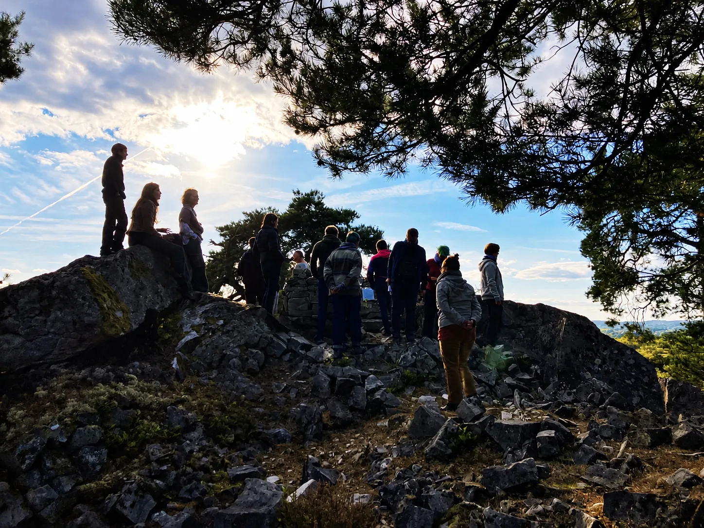 Un groupe de promeneurs debout sur un rocher au coucher du soleil, à l'écoute